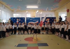 Kalina powiewa dużą polską flagą, dzieci śpiewają piosenkę